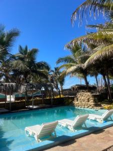 una piscina con due sedie a sdraio e palme di Bali Lodge Máncora - Playa, Piscina & Desayuno a Máncora