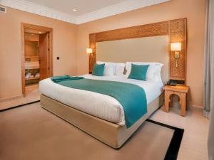 a large bedroom with a large bed with blue pillows at Kenzi Azghor in Ouarzazate