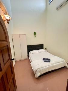 a bedroom with a white bed with a black headboard at IF Homestay Mersing in Mersing