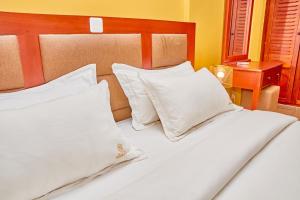 Résidence Belmann في دوالا: سرير بشرشف ووسائد بيضاء في الغرفة +صورتان