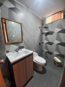 a bathroom with a toilet and a sink and a mirror at Hospedaje Hamuy's Lodge in Ica