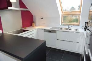 a kitchen with white cabinets and a sink and a window at Gîte Fenêtres sur cour - Genappe in Genappe