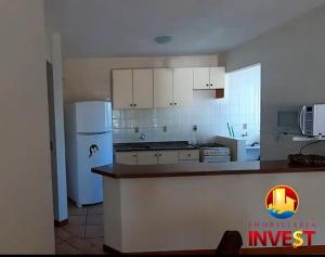 een keuken met witte kasten en een witte koelkast bij Cobertura duplex Bombas in Bombinhas +10 foto's