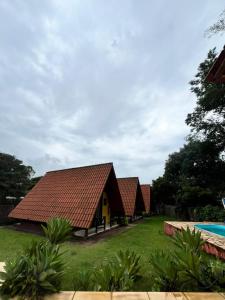 a row of cottages with a pool in the yard at Chalés Dinhá-Pousada Recanto do Rapa in Brumadinho