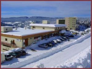 a large building with cars parked in the snow at Chaleureux studio pied des pistes Les Glovettes VILLARD DE LANS in Villard-de-Lans