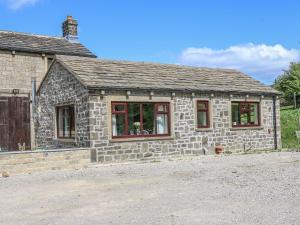 a stone house with red windows on a dirt road at Baywood Cottage in Keighley