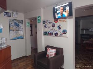 a living room with a chair and a tv on a wall at HOTEL San Antonio in Puno