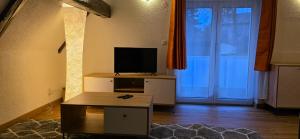 a living room with a television and a table and a door at Ferienwohnung "Dachblick" Bad Elster in Bad Elster