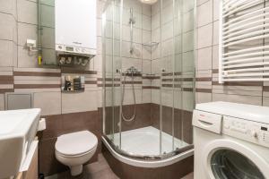 a bathroom with a toilet a sink and a washing machine at Katowice Central Apartment by BookingHost in Katowice