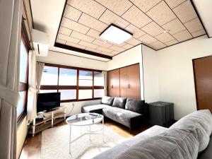 a living room with a couch and a table at 2025年12月OPEN! 豊橋民泊 最大13名様 駐車場2台無料 駅徒歩7分 Traditional Japanese house ,Toyohashi Aichi in Toyohashi