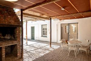 a patio with a brick fireplace and a table and chairs at Cottage at 48 in Graaff-Reinet
