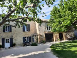 ein altes Steinhaus mit blauen Fensterläden in der Unterkunft La Grange Bessac in Violès