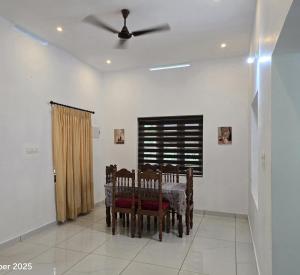 a dining room with a table and chairs and a ceiling fan at Thiruthi Homestay in Vallikunnu