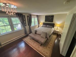 滨湖尼亚加拉Vintage Pines Guest House的一间卧室，里面有一张床、一把椅子和几扇窗户。