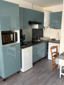 een keuken met blauwe kasten en een magnetron bij La petite boucane in Fécamp +2 foto's