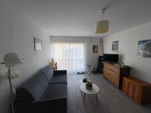 een woonkamer met een blauwe bank en een tafel bij La petite boucane in Fécamp