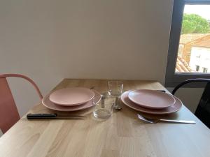 a wooden table with two plates and glasses on it at V2 Studio avec balcon, plein centre - 5 min Golfech in Valence-dʼAgen