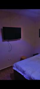 a bedroom with a bed and a flat screen tv on the wall at Abasis apartment in Abeokuta