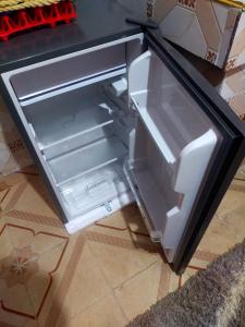 an empty refrigerator with its door open on a kitchen floor at Mini farmhouse in Kakamega