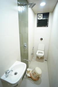a white bathroom with a sink and a toilet at Hotel Sai Pratham in Shirdi