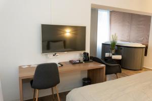 una camera d'albergo con scrivania e TV a parete di Hotel Work Life Residence am Bahnhof a Winterthur Altre 8 foto