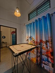 Una mesa de ping pong en una habitación con una cortina. en Hestia by Ghorsirika, en Guwahati