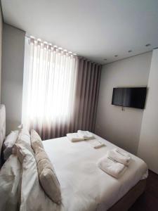 Un dormitorio con una gran cama blanca con toallas. en Terro Collection - Souto 23, en Braga