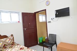 Habitación con cama, puerta y silla en Gugan home stay, en Tiruchchendūr 21 fotos más