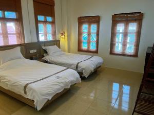 Duas camas num quarto com janelas em Tea time B&B em Luang Prabang