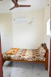 a small bed in a room with a ceiling fan at Gugan home stay in Thiruchendur