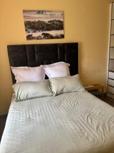 a bed with white sheets and pillows in a bedroom at Hatfield - Staylax Manor 3 in Harare