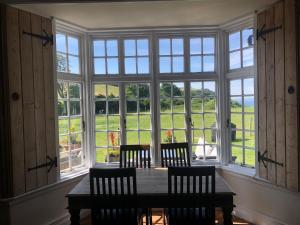 St Annes House Double Room 5 في بلايموث: غرفة طعام مع طاولة وكراسي ونوافذ كبيرة