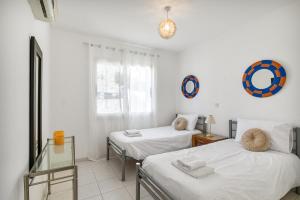 two beds in a room with white walls at Kastalia Springs 3bd VIilla in Peiya by VICHY Holidays in Peyia