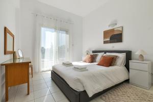 a bedroom with a bed and a desk and a window at Kastalia Springs 3bd VIilla in Peiya by VICHY Holidays in Peyia