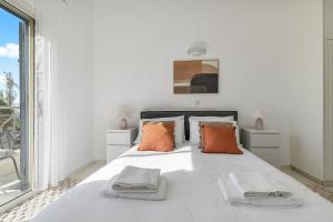 a white bedroom with a large white bed with orange pillows at Kastalia Springs 3bd VIilla in Peiya by VICHY Holidays in Peyia