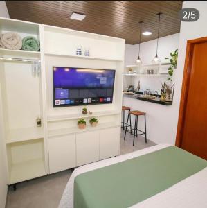 a living room with a tv in a white wall at Flat Aconchego dos Pássaros in Bonito +3 photos