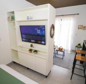 a white entertainment center with a flat screen tv in a living room at Flat Aconchego dos Pássaros in Bonito