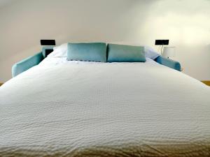 Vivienda Unifamiliar Ventana a la Clerecía في سلامنكا: سرير أبيض كبير مع وسادتين زرقاوين عليه +10 صور