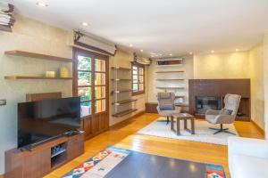 uma sala de estar com uma televisão de ecrã plano e uma lareira em Espectacular casa con piscina próxima a Pamplona em Zizur Mayor