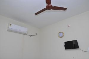 a ceiling fan and a clock on a wall at Gugan home stay in Tiruchchendūr