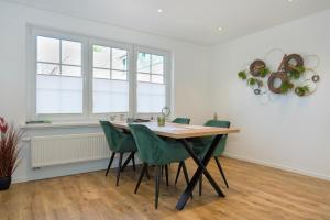 ein Esszimmer mit einem Tisch und grünen Stühlen in der Unterkunft Klosterhof Aue W 3 in Bad Zwischenahn + 14 Fotos