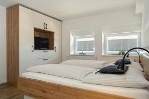 1 Schlafzimmer mit einem Bett, einem TV und 2 Fenstern in der Unterkunft Klosterhof Aue W 3 in Bad Zwischenahn