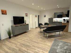 ein Wohnzimmer mit Fernseher und Tisch und Stühlen in der Unterkunft Klosterhof Aue W 14 in Bad Zwischenahn