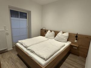 ein Schlafzimmer mit einem Bett mit weißen Laken und Kissen in der Unterkunft Klosterhof Aue W 14 in Bad Zwischenahn