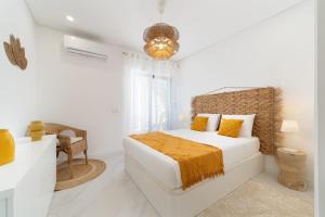 een witte slaapkamer met een bed en een stoel bij CASINHA Do FAROL in Praia do Carvoeiro
