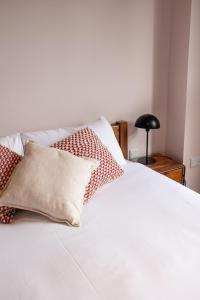 ein weißes Bett mit roten und weißen Kissen darauf in der Unterkunft Malacuna Manchester in Manchester