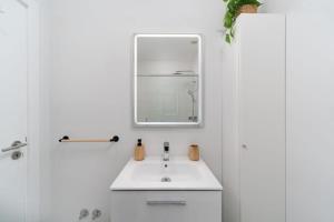 een witte badkamer met een wastafel en een spiegel bij CASINHA Do FAROL in Praia do Carvoeiro +50 foto's