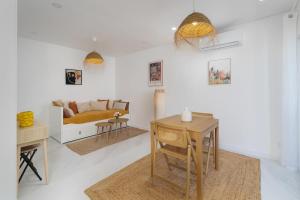 een witte woonkamer met een bed en een tafel bij CASINHA Do FAROL in Praia do Carvoeiro