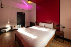 ein Schlafzimmer mit einem großen Bett mit einer roten Wand in der Unterkunft Malacuna Manchester in Manchester