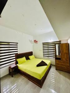 a bedroom with a bed with yellow sheets and yellow pillows at Guest arc Residency in Sultan Bathery